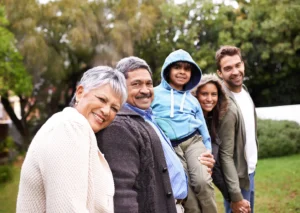 A happy multi-generational family in a park, emphasizing the importance of gum health and healthy habits across all ages - Big Sky Family Dental.