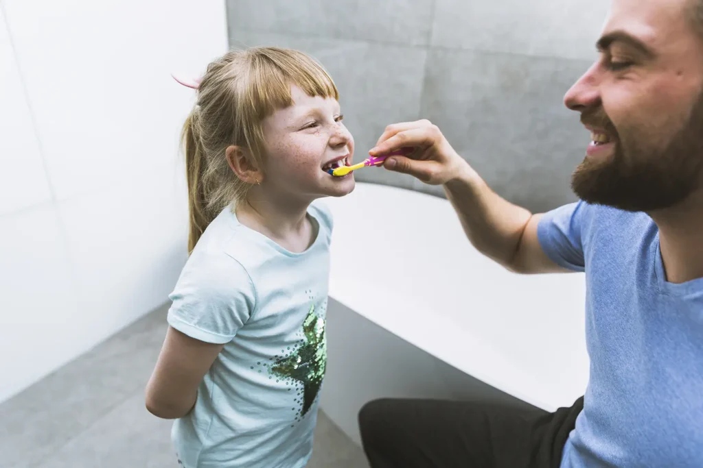 A father brushing his daughter's teeth, promoting healthy habits and gum health - Big Sky Family Dental.