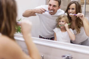 A family practicing dental hygiene together by brushing their teeth, promoting the importance of good habits for a healthy smile, supported by Big Sky Family Dental.