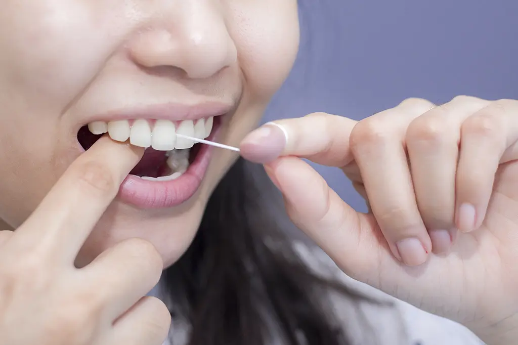 Close-up of a woman using dental floss, emphasizing the role of oral health in the heart connection. Big Sky Family Dental provides insights on maintaining dental hygiene for whole-body health.