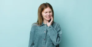 A woman in discomfort is holding her cheek, indicating a painful toothache, possibly due to teeth sensitivity. This image represents the common concern of "my teeth hurt." For expert care and relief, Big Sky Family Dental in Billings, MT provides comprehensive dental services to address and manage tooth sensitivity effectively.