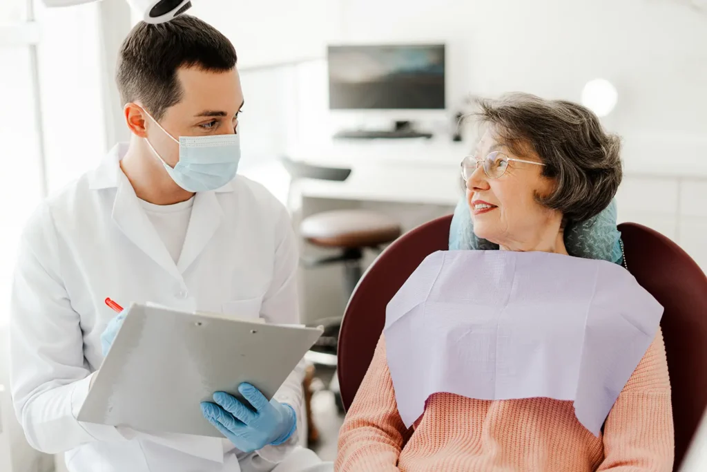 A young dentist discussing tooth decay and treatment options with an elderly patient at Big Sky Family Dental.