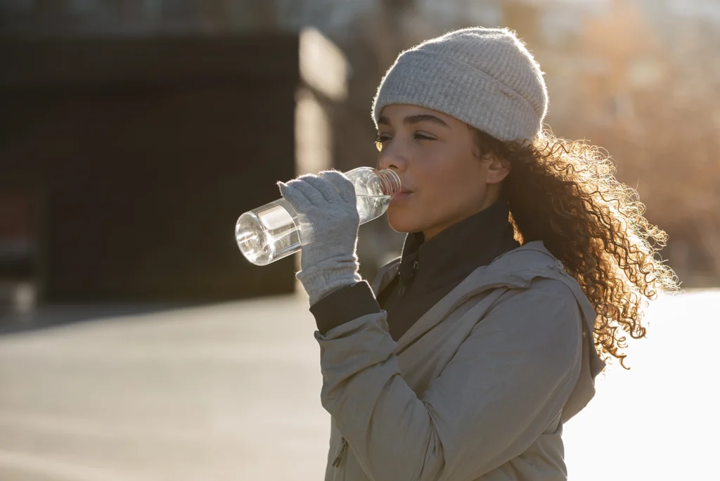 A woman staying hydrated by drinking water, which helps promote healthy saliva production. Big Sky Family Dental highlights the importance of maintaining adequate saliva levels to support oral health and prevent issues like dry mouth.